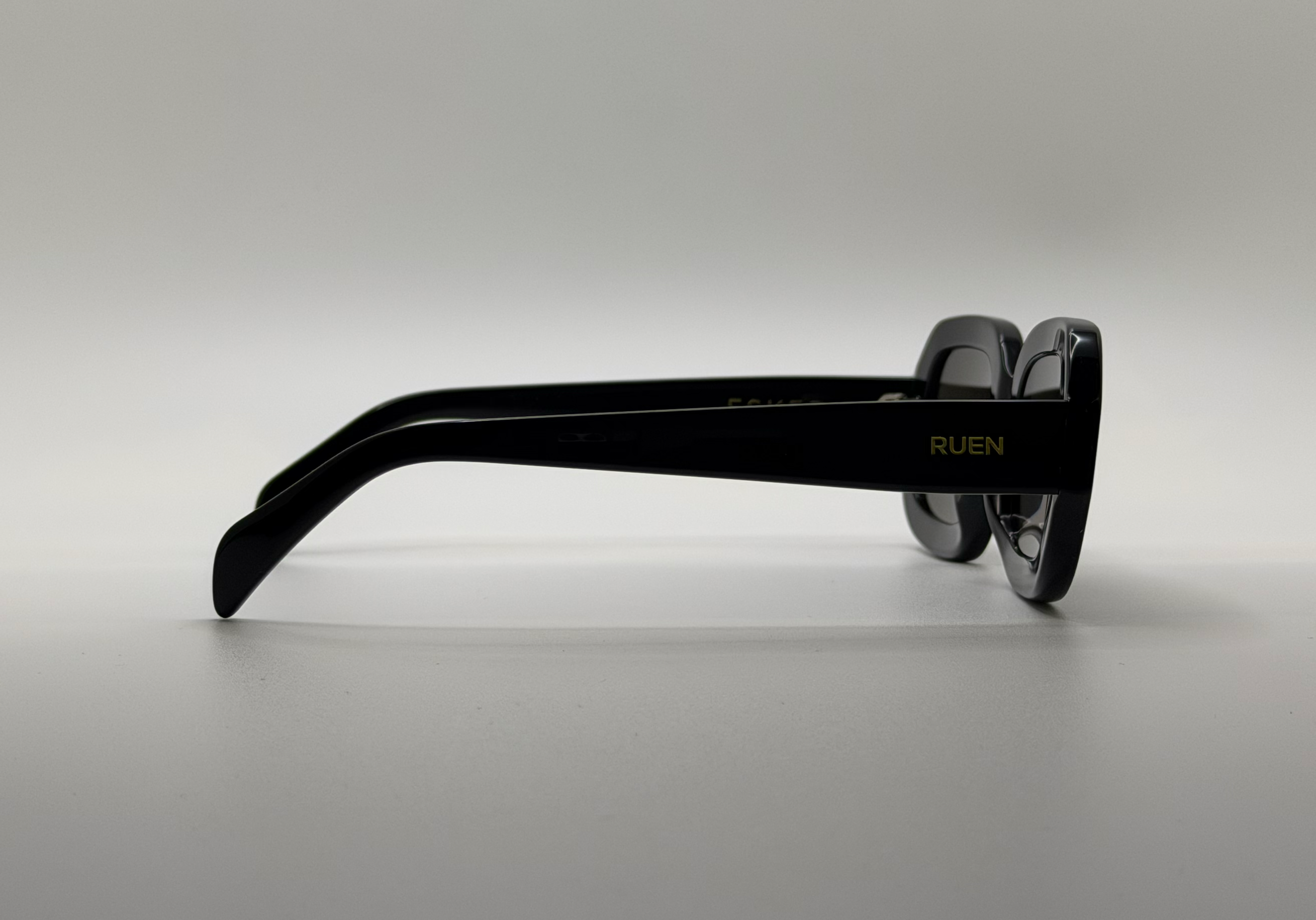 Black sunglasses with 'RUEN' branding on a gray background