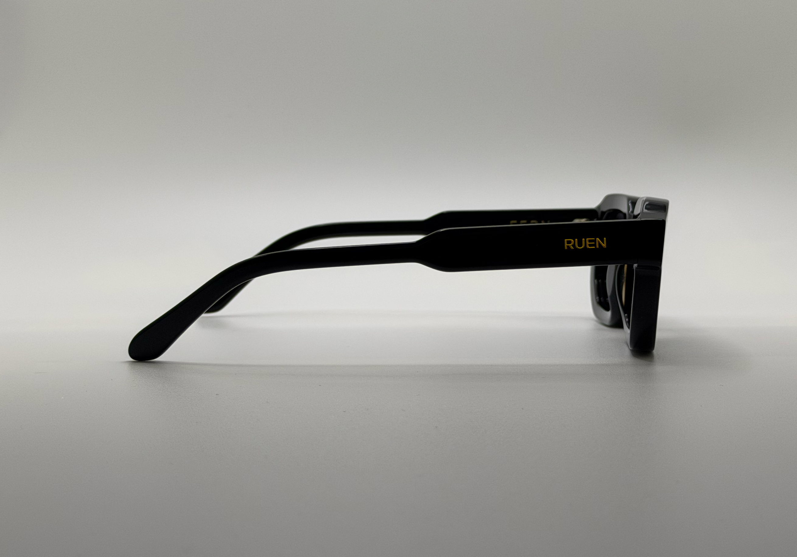 Black sunglasses with 'RUEN' branding on a gray background