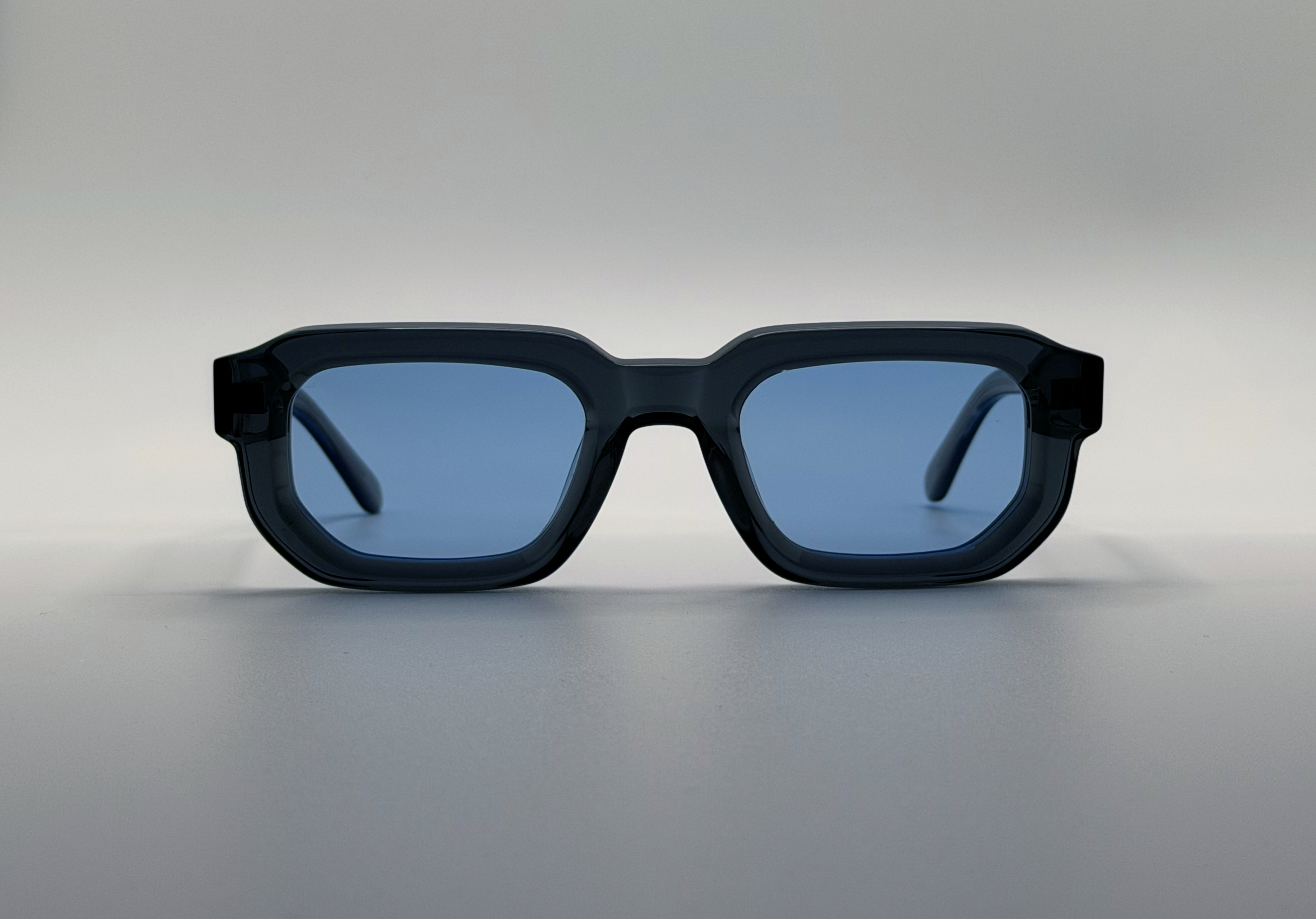 Blue sunglasses with blue lenses on a gray background
