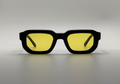 Black sunglasses with yellow lenses on a gray background