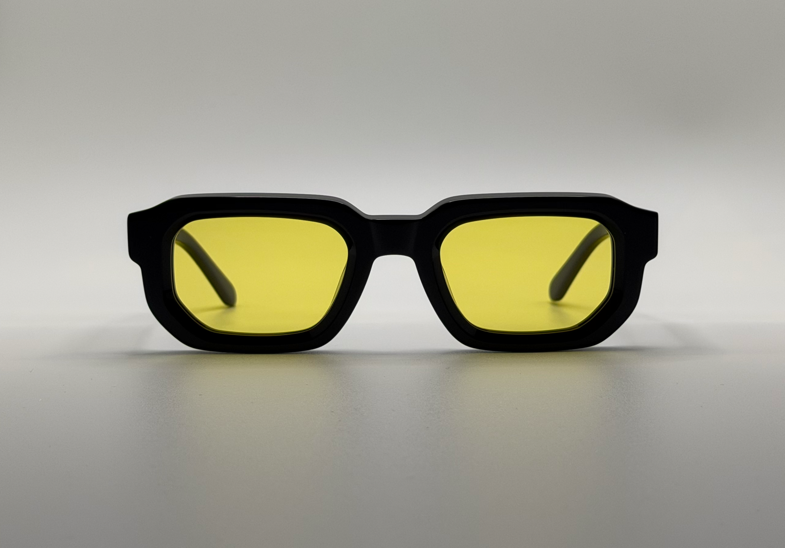 Black sunglasses with yellow lenses on a gray background