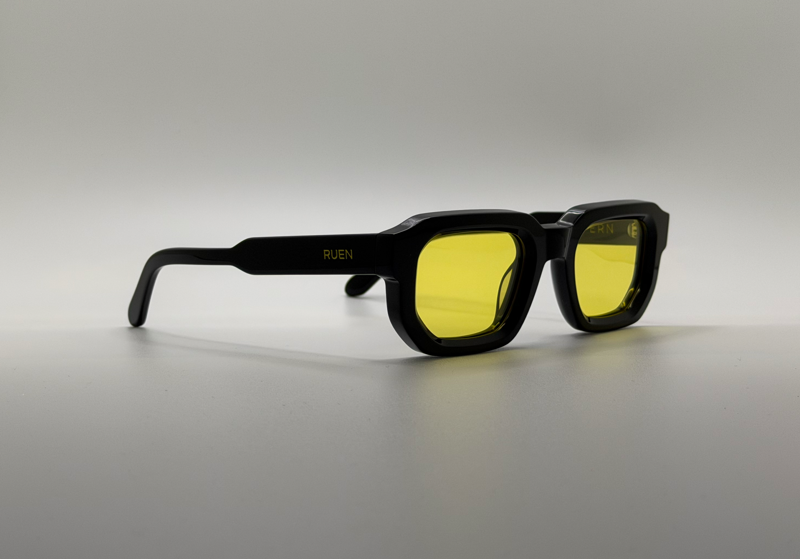 Black sunglasses with yellow lenses on a gray background