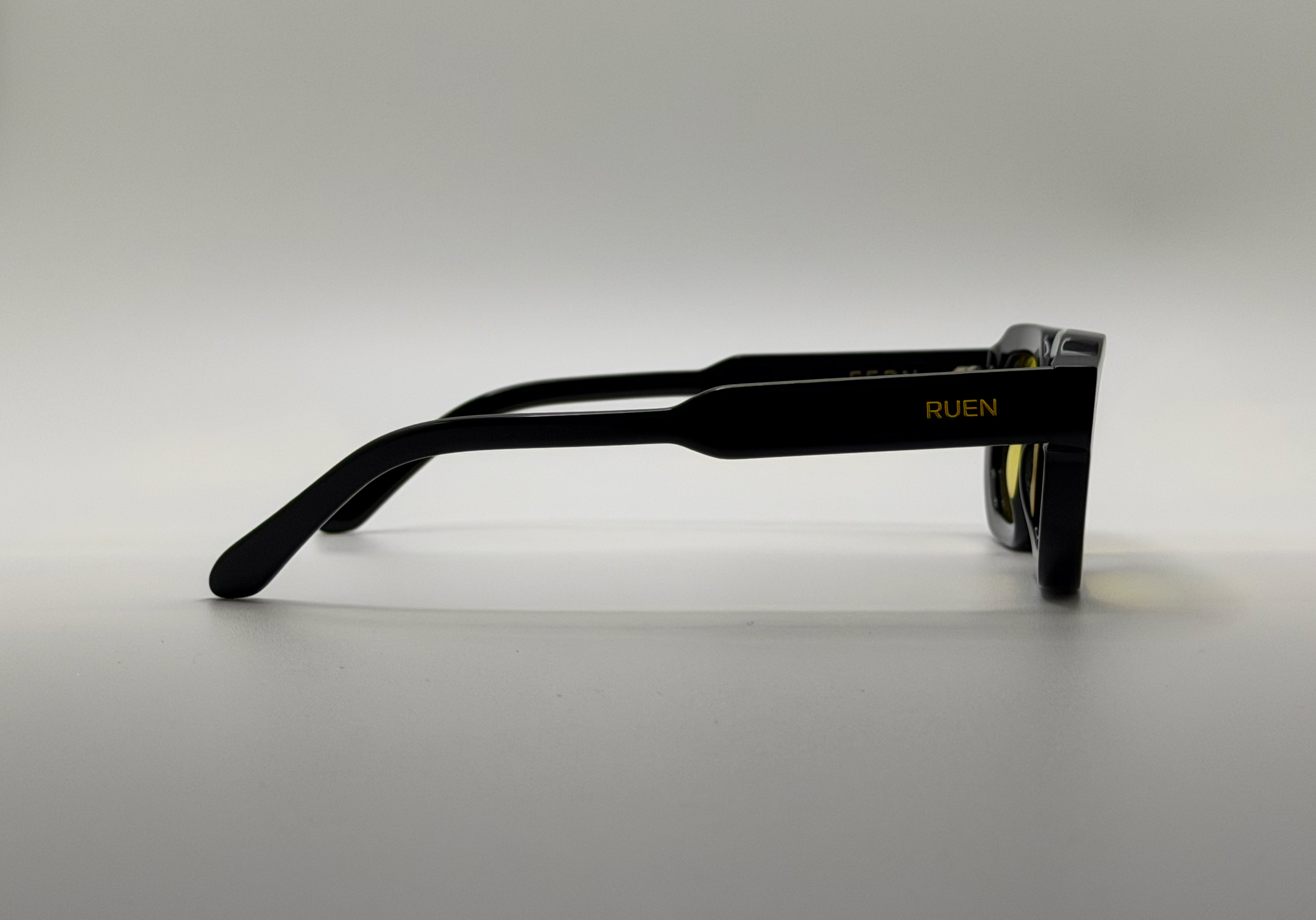 Black sunglasses with 'RUEN' branding on a gray background