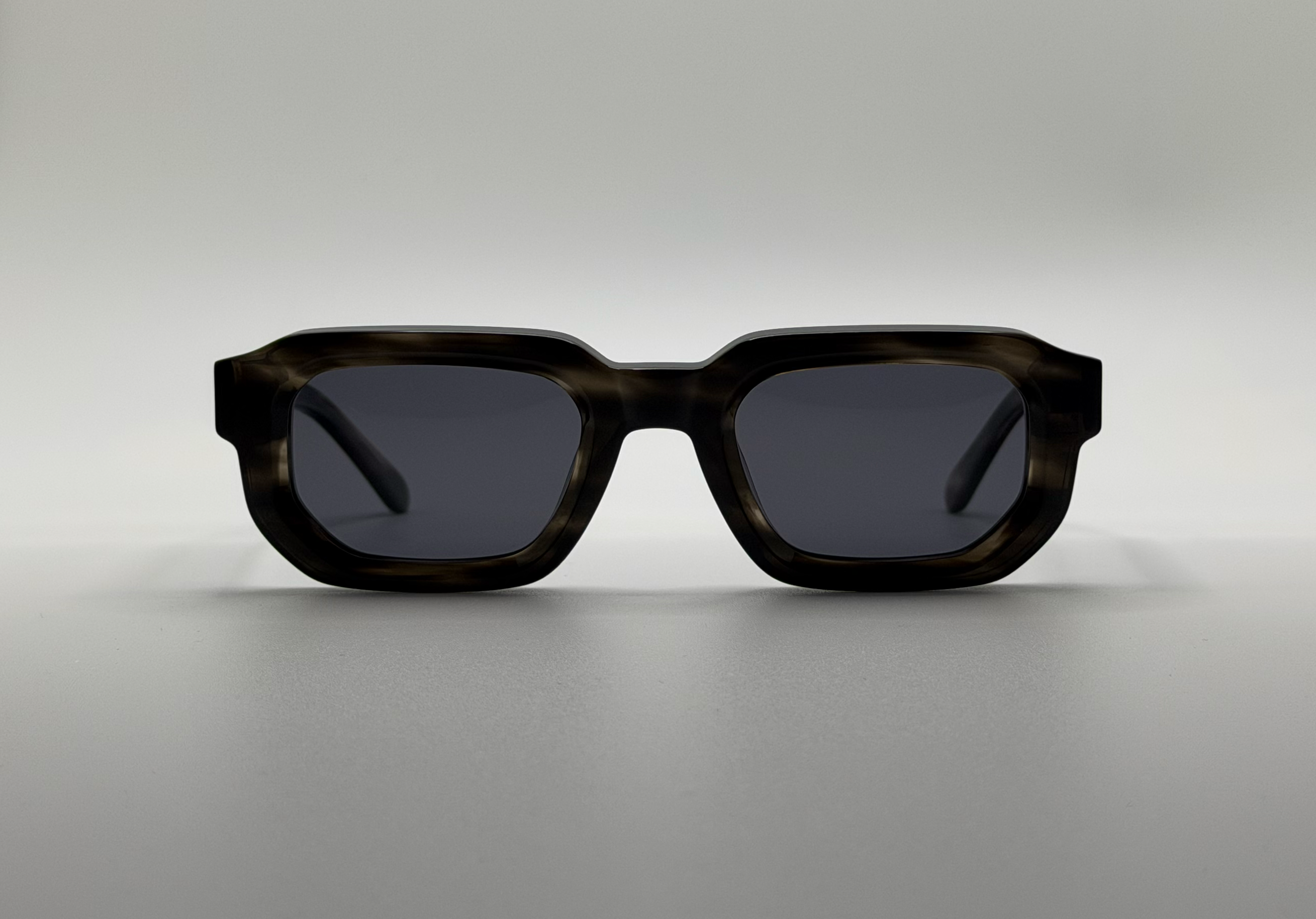 Sunglasses with a tortoiseshell frame on a light gray background