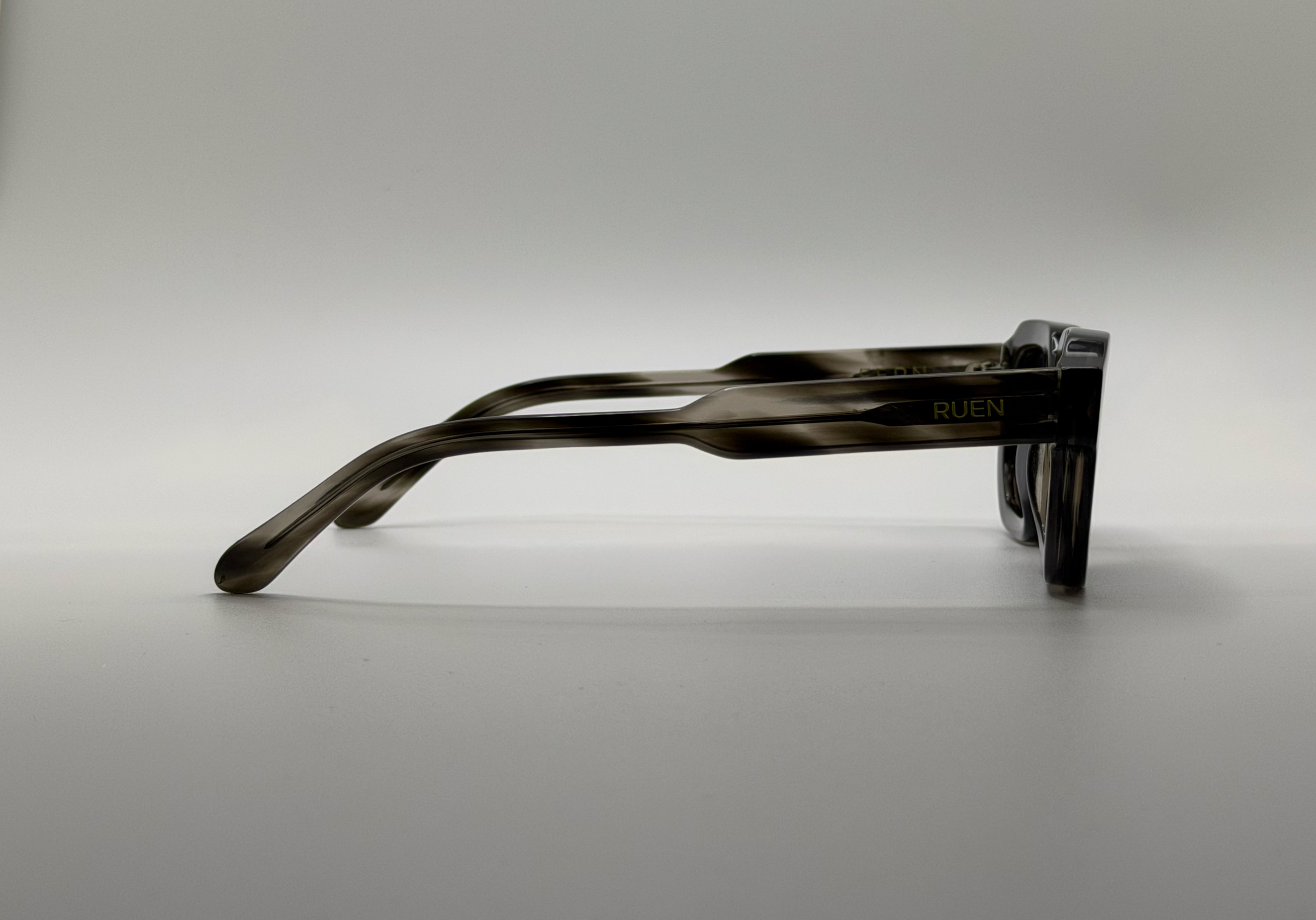 Black sunglasses with 'RUEN' branding on a gray background