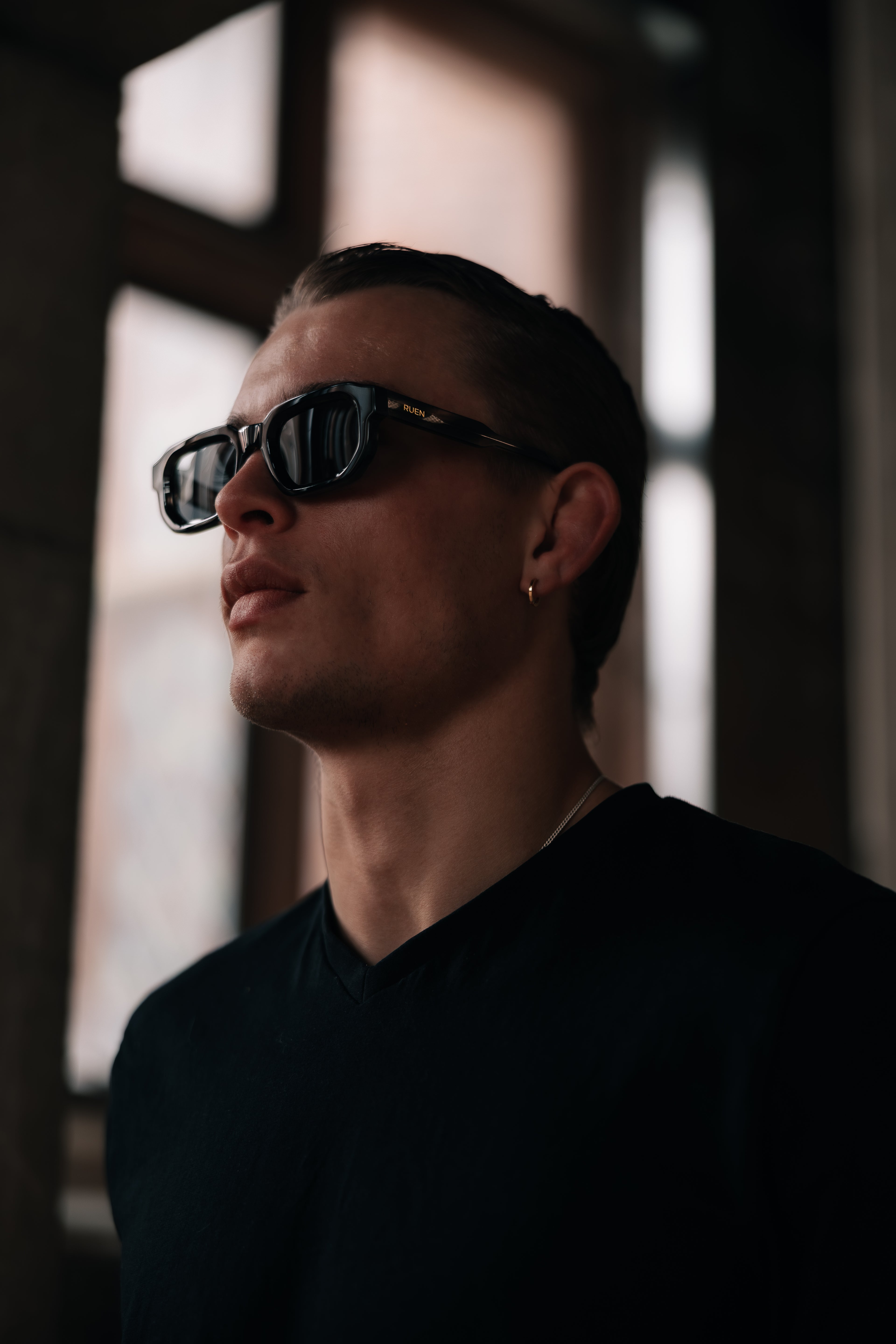Man wearing dark sunglasses in a dimly lit room