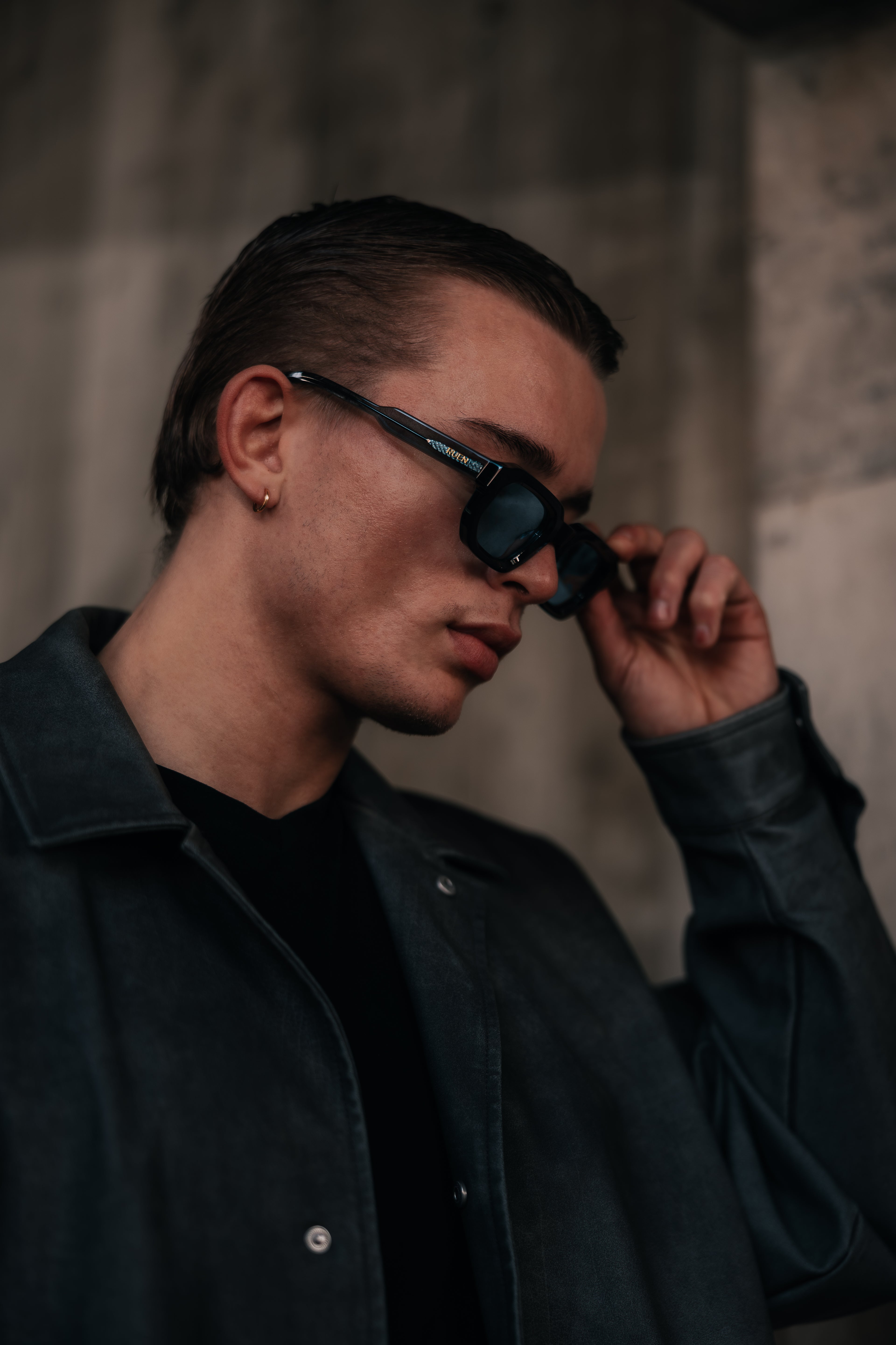 Man adjusting sunglasses against a neutral background