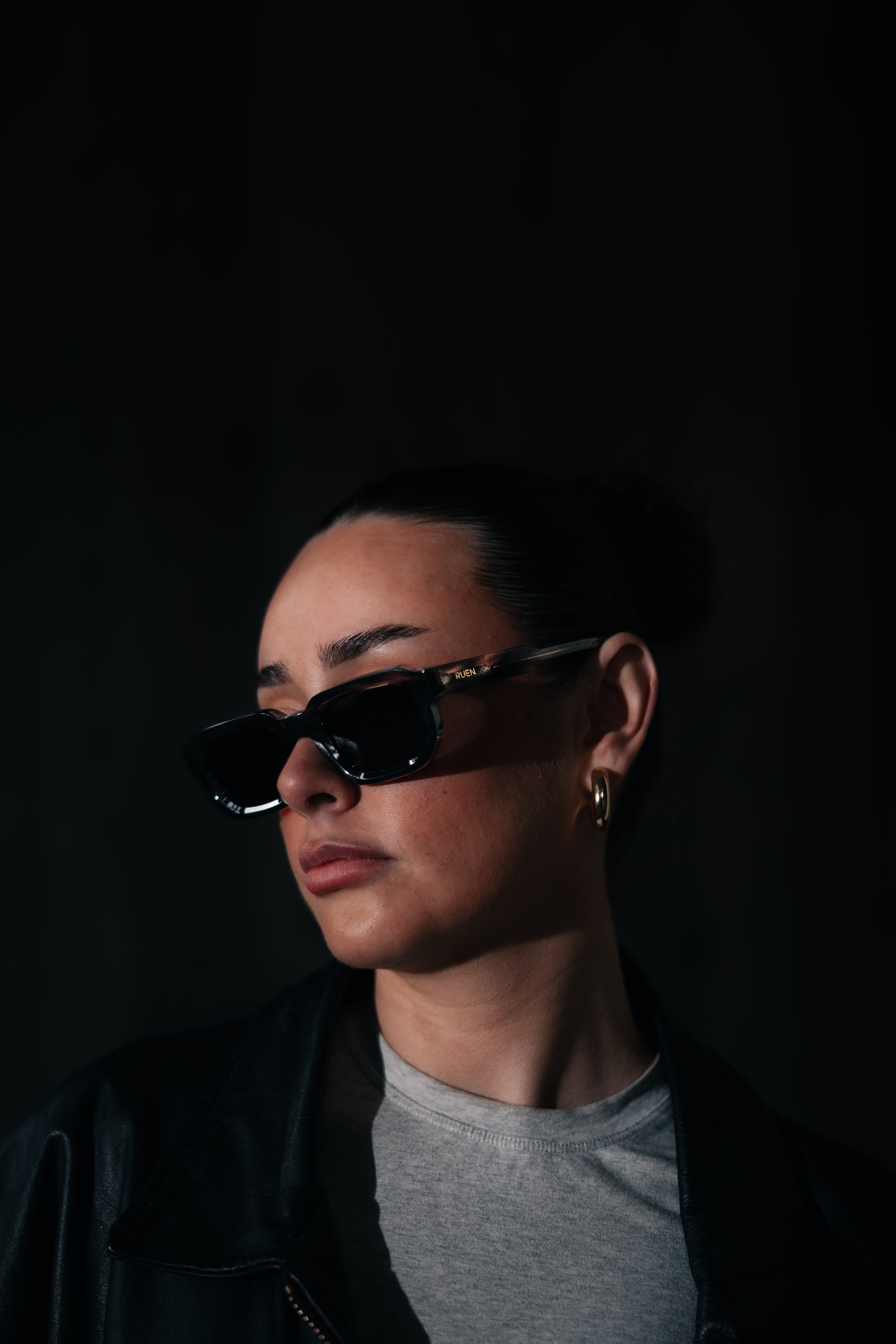 Person wearing black sunglasses against a dark background