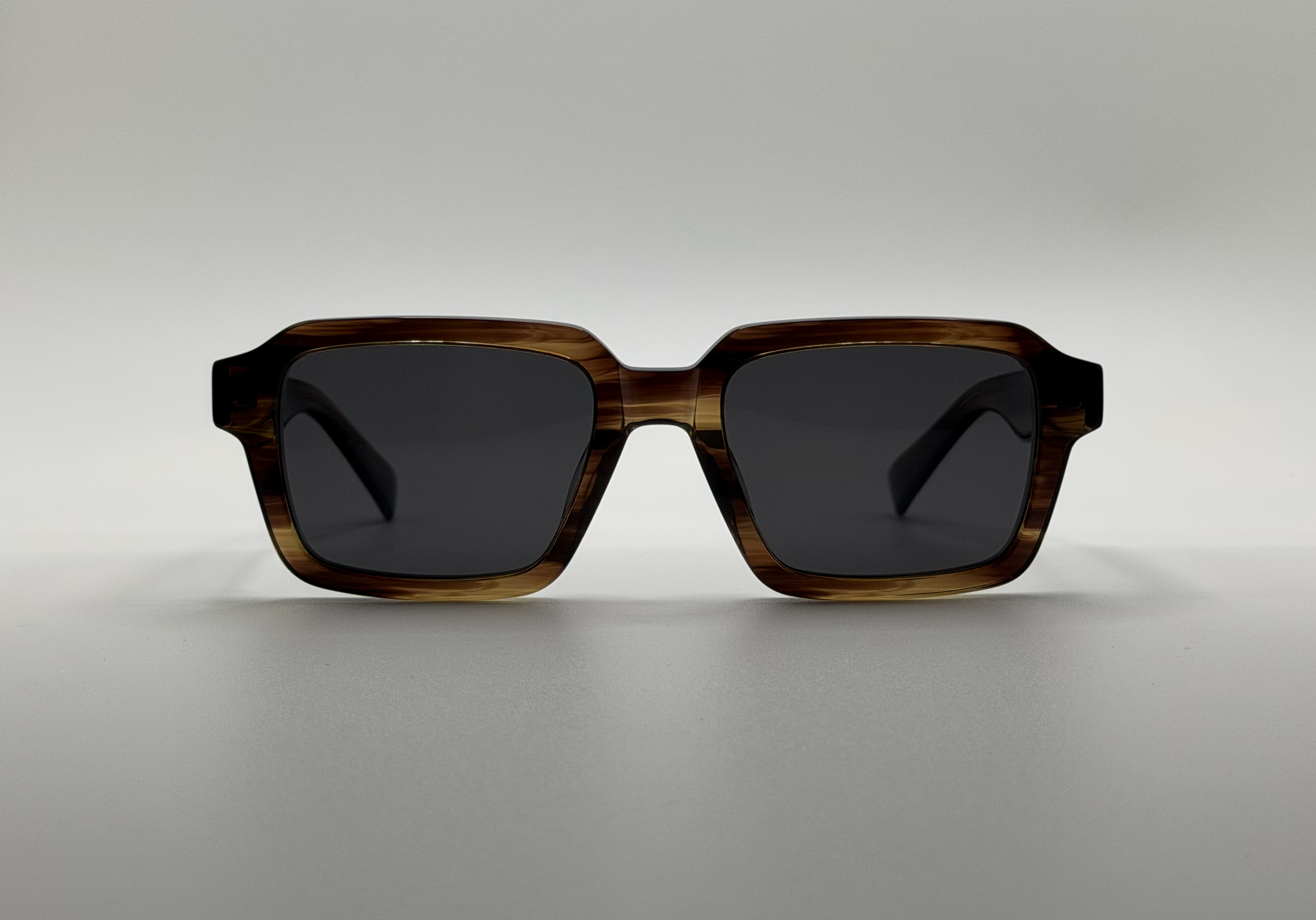 Sunglasses with a tortoiseshell frame on a light gray background