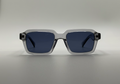 Sunglasses with a clear frame and dark lenses on a gray background