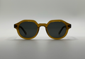 Sunglasses with gold frame and dark lenses on a light gray background