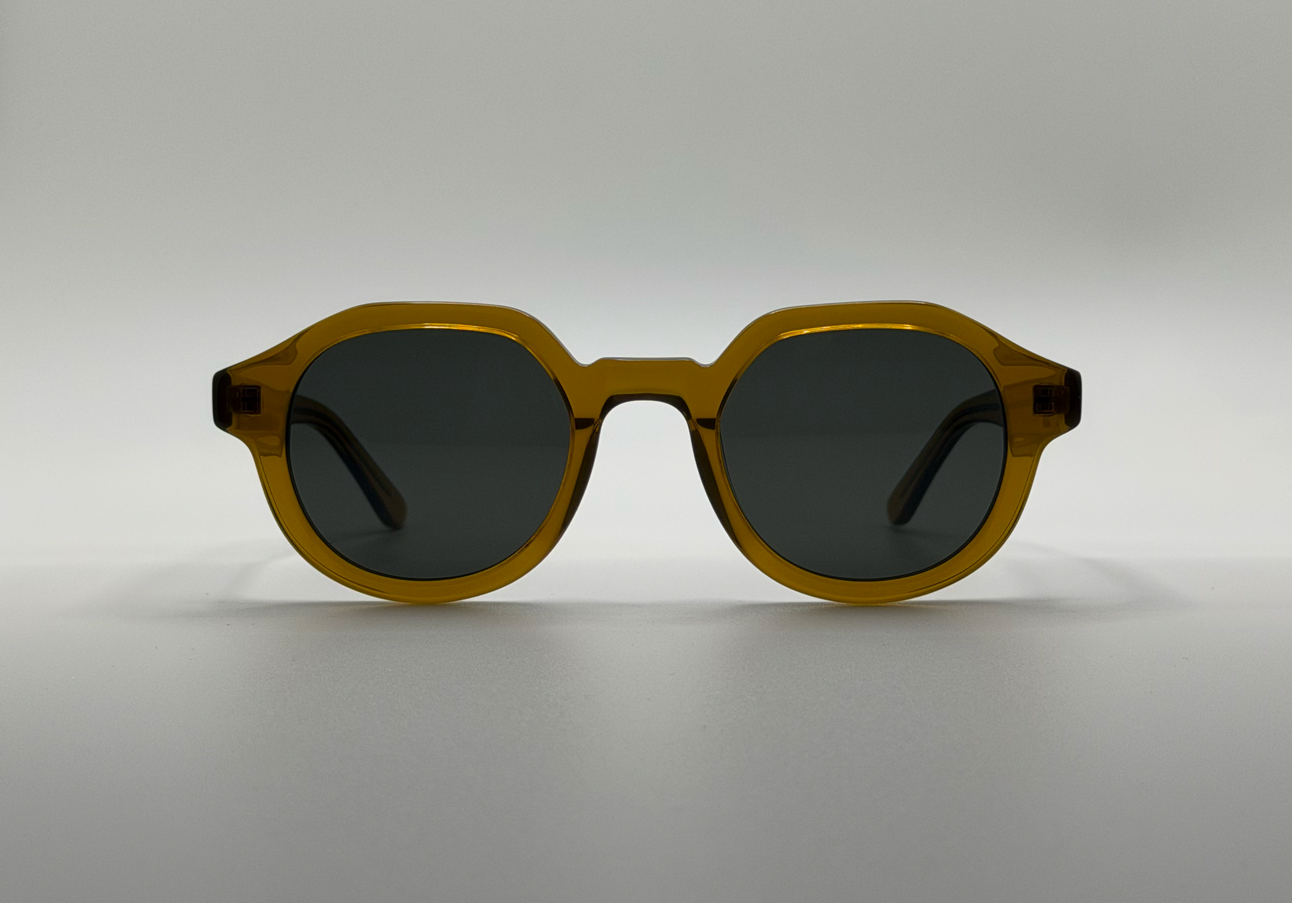 Sunglasses with gold frame and dark lenses on a light gray background