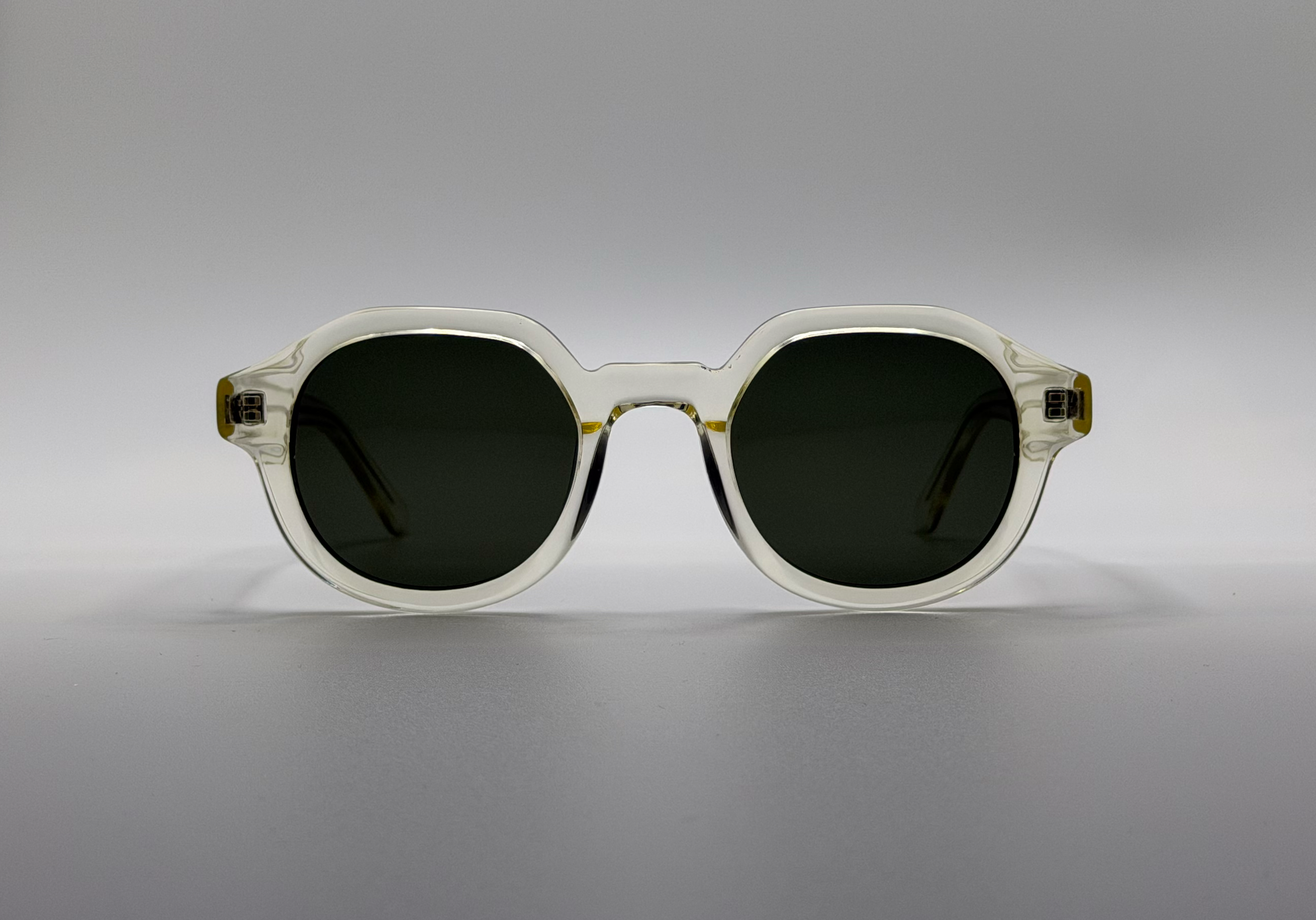 Sunglasses with a clear frame and dark lenses on a gray background