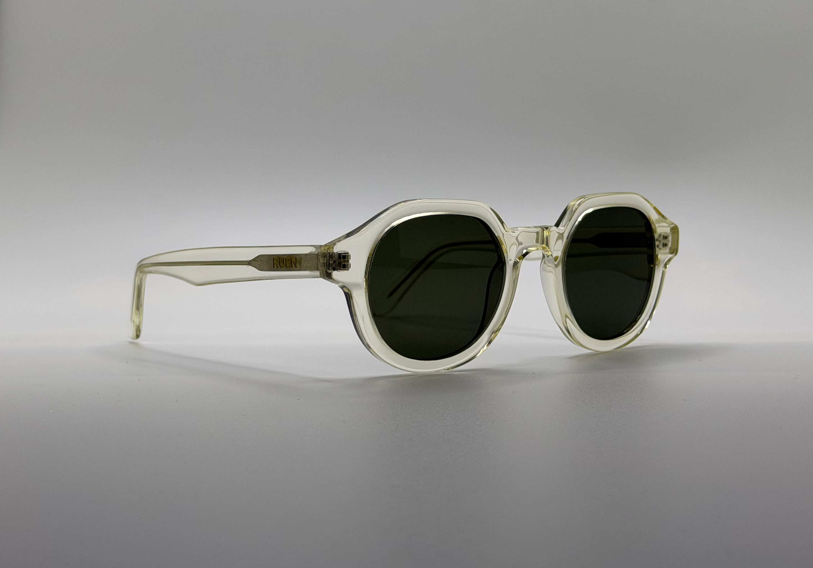 Sunglasses with transparent frame and dark lenses on a gray background