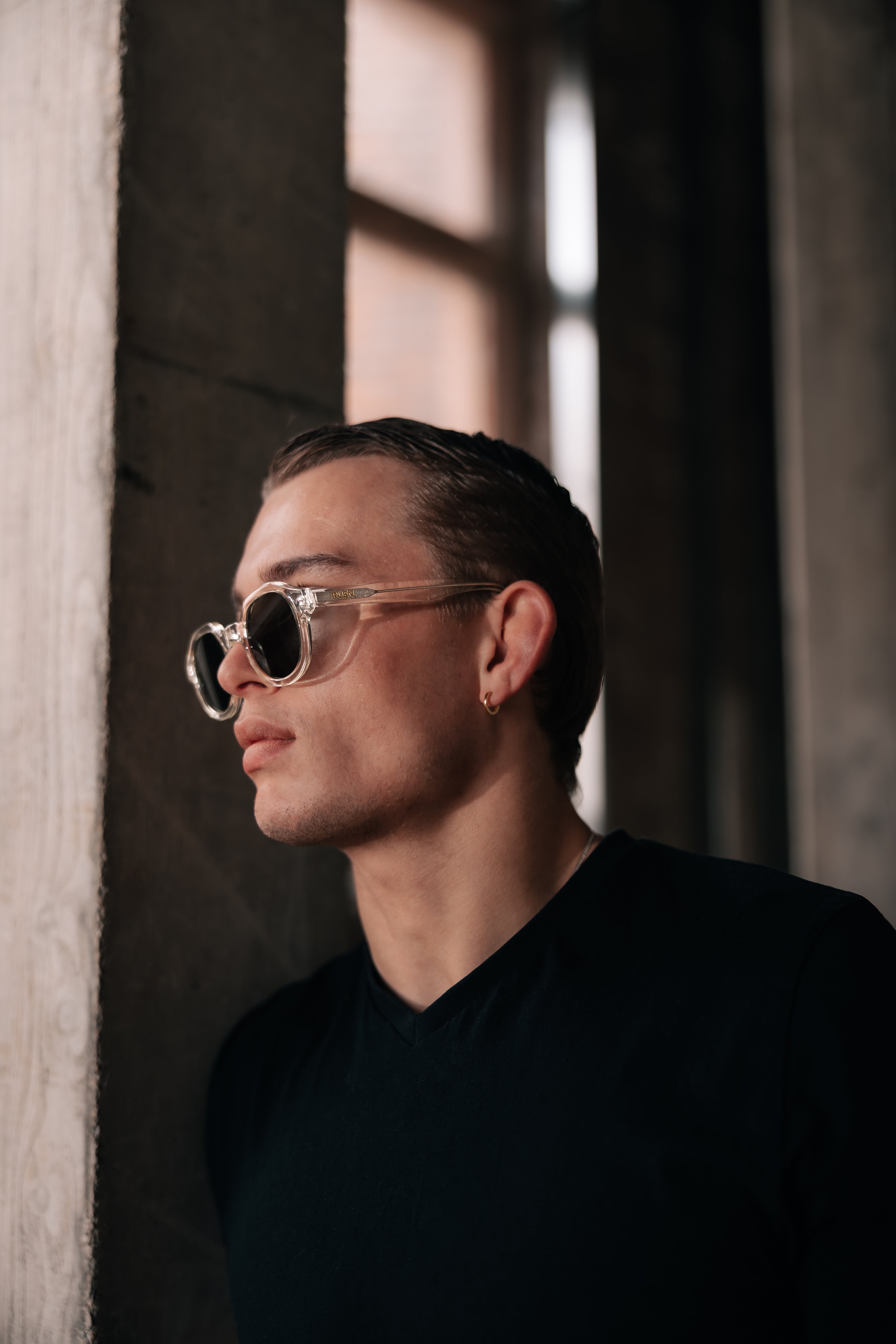 Man wearing sunglasses and a black shirt in a dimly lit room